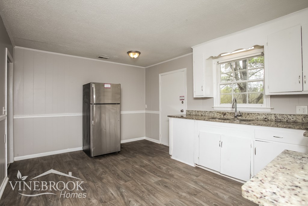 A kitchen with white cabinets and a stainless steel refrigerator.