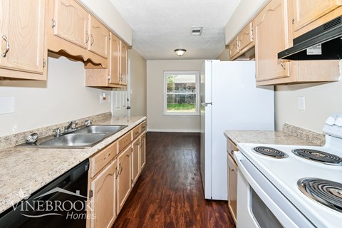 A kitchen with wooden cabinets and a white stove top oven.