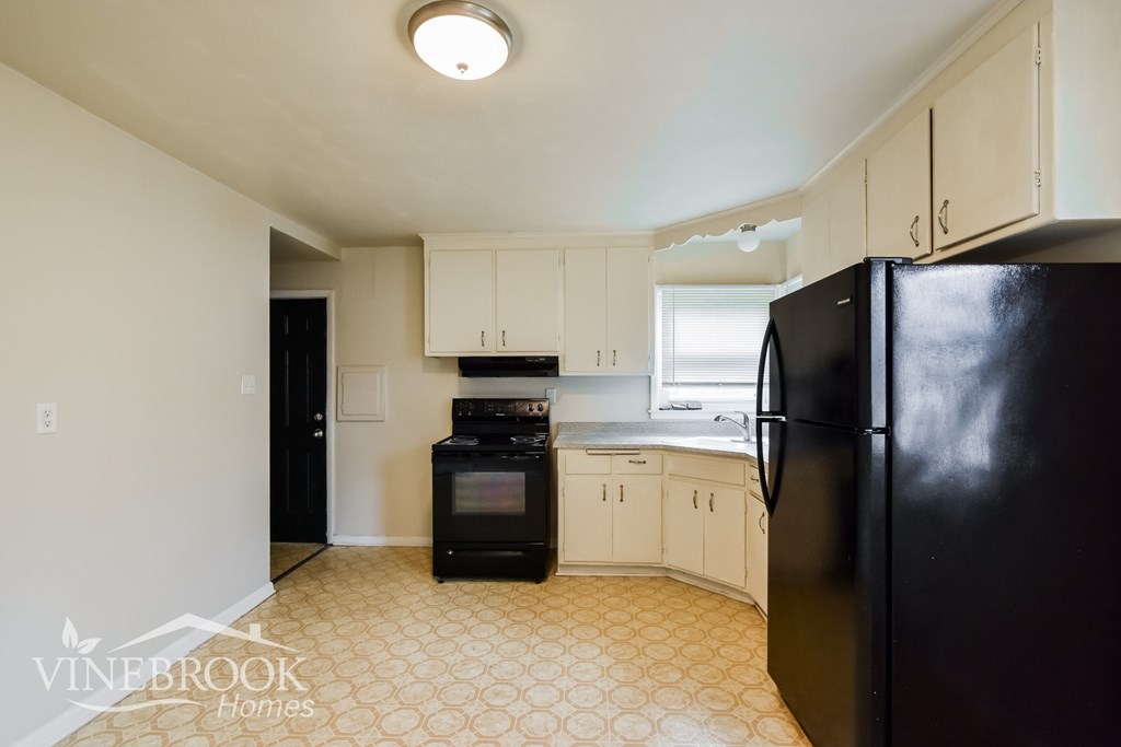 A kitchen with black appliances and white cabinets.