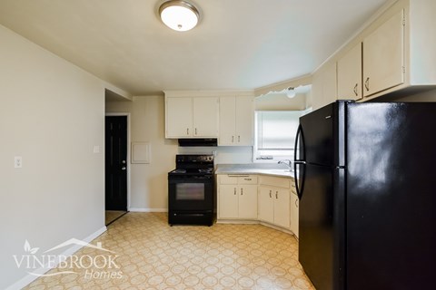 A kitchen with black appliances and white cabinets.