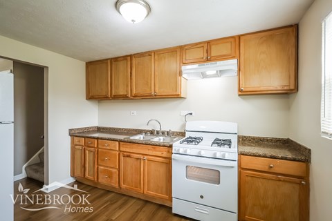 A kitchen with wooden cabinets and a white stove top oven.
