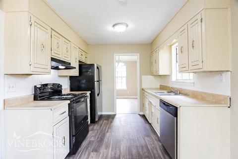 A kitchen with black appliances and white cabinets.