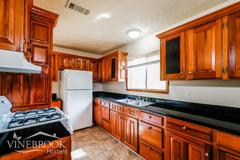 A kitchen with wooden cabinets and a Vinebrook Homes sign.