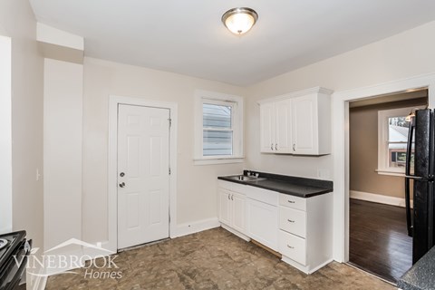 A kitchen with white cabinets and a black countertop.