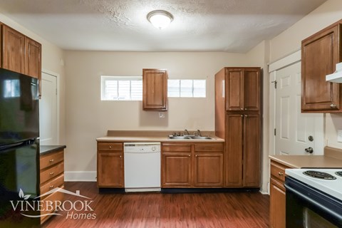 A kitchen with wooden cabinets and a black fridge.