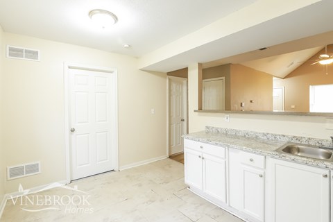 A white kitchen with a sink and a mirror.