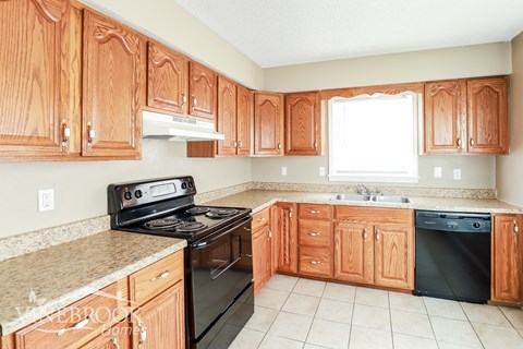A kitchen with wooden cabinets and a black stove top oven.