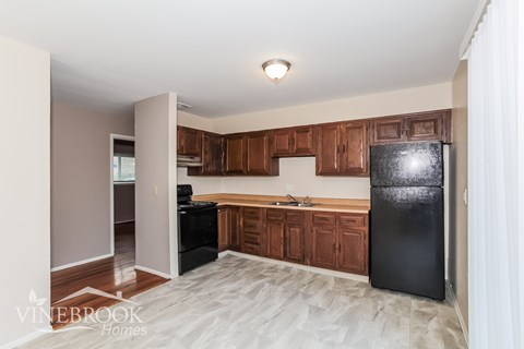 A kitchen with black appliances and wooden cabinets.