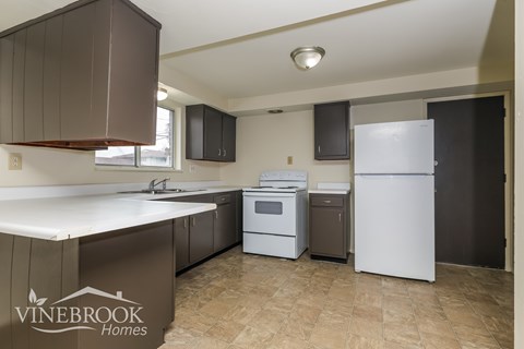 A kitchen with a white fridge and brown cabinets.