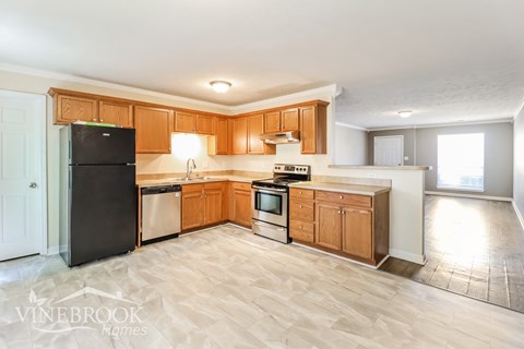 A kitchen with wooden cabinets and a black refrigerator.