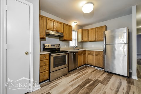 A kitchen with wooden cabinets and a stainless steel refrigerator.