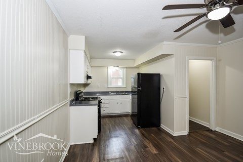 A kitchen with a black refrigerator and white cabinets.