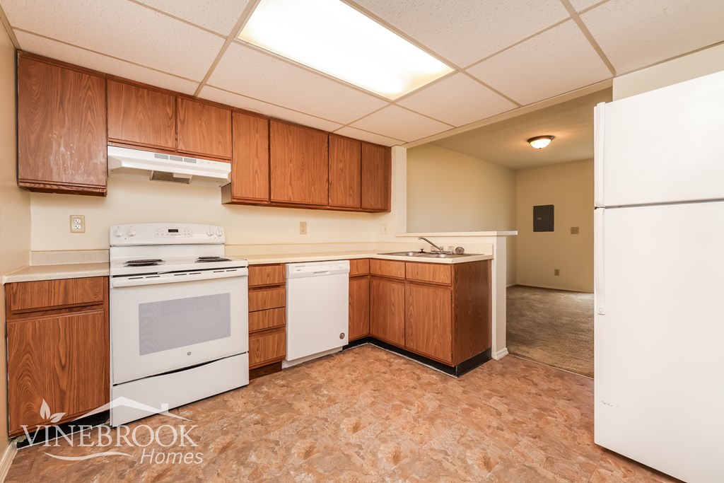 A kitchen with white appliances and wooden cabinets.