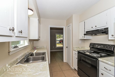 A kitchen with white cabinets and a black stove top oven.