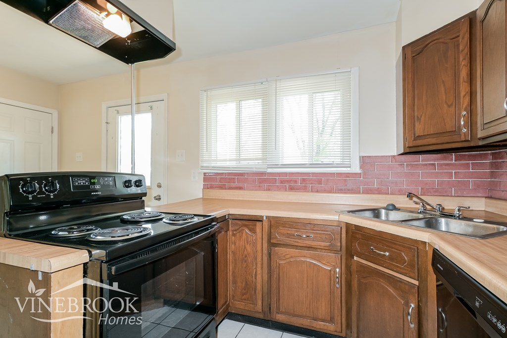 A kitchen with wooden cabinets and a black stove top oven.