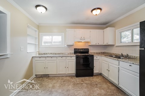 A kitchen with a black oven and white cabinets.