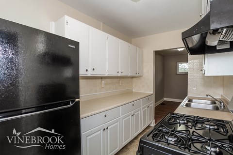 A kitchen with a black fridge and a stove top oven.