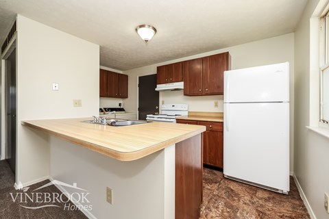 A kitchen with a white refrigerator and wooden countertops.