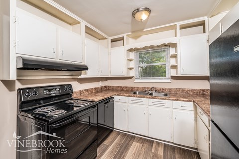 A kitchen with a black stove top oven and white cabinets.