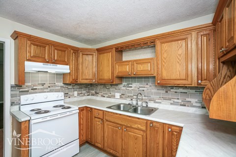 A kitchen with wooden cabinets and a white stove.