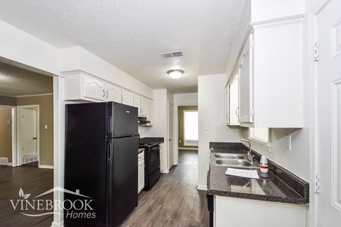 A kitchen with a black fridge and white cabinets.