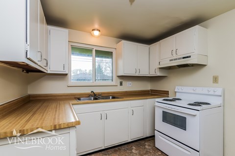 A kitchen with white cabinets and a white stove top oven.