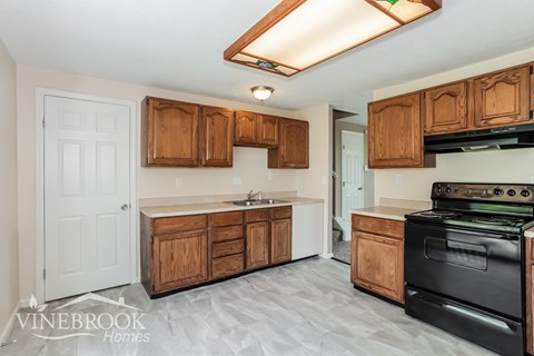 A kitchen with wooden cabinets and a black stove top oven.