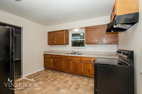 A kitchen with a black fridge and black stove top oven.