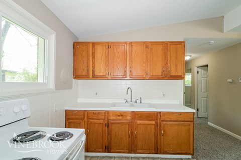 A kitchen with wooden cabinets and a white stove top oven.
