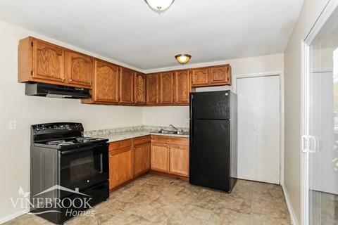 A kitchen with black appliances and wooden cabinets.