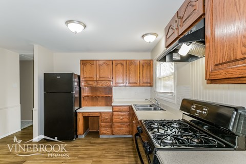 A kitchen with wooden cabinets and a black fridge.