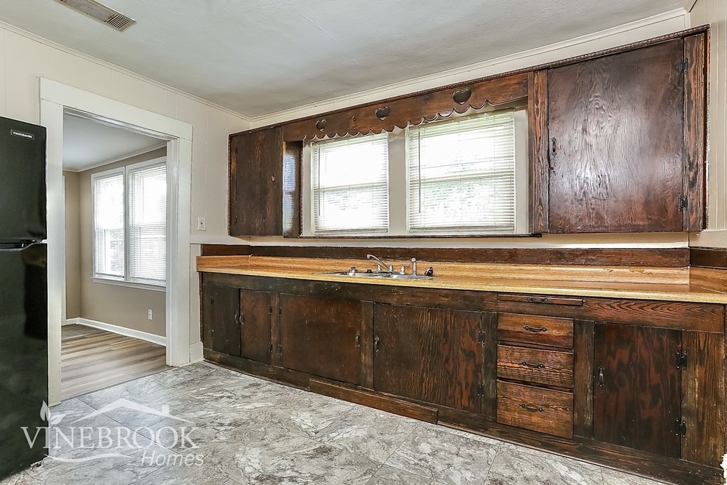 A kitchen with a wooden cabinet and a black fridge.