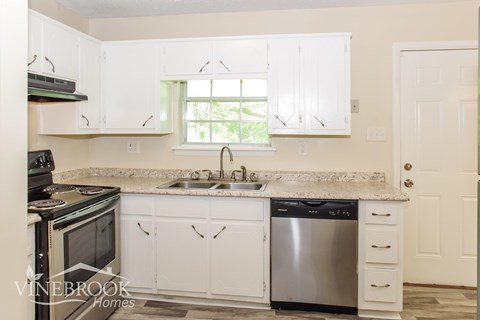 A kitchen with white cabinets and a stainless steel dishwasher.