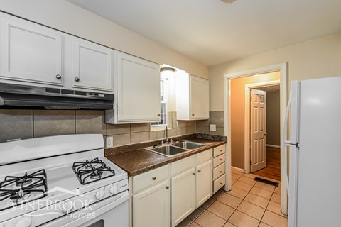 A kitchen with white cabinets and a white stove.