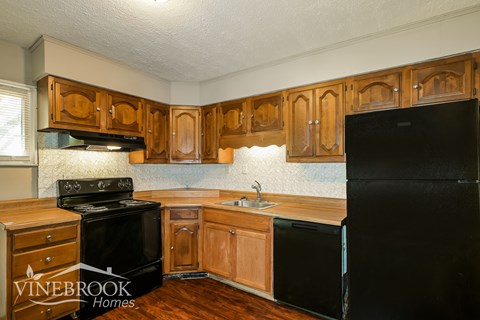A kitchen with wooden cabinets and black appliances.