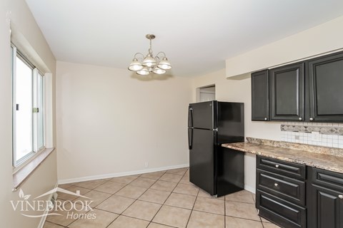 A kitchen with black cabinets and a black refrigerator.
