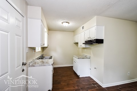 A kitchen area with a fridge, stove and cabinets.