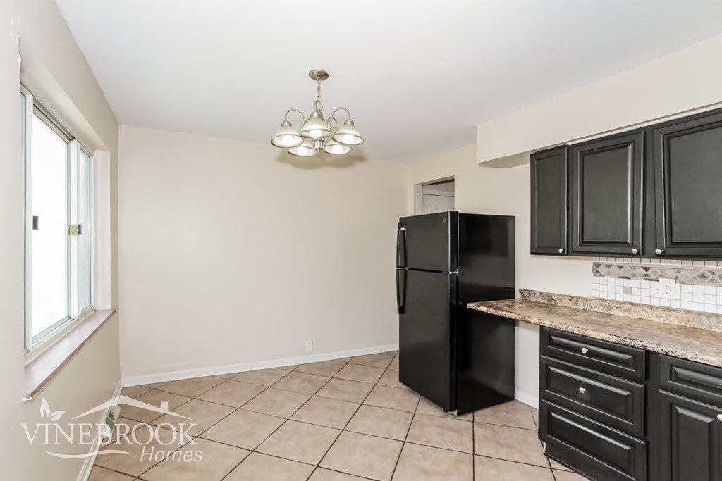 A kitchen with a black fridge and cabinets.