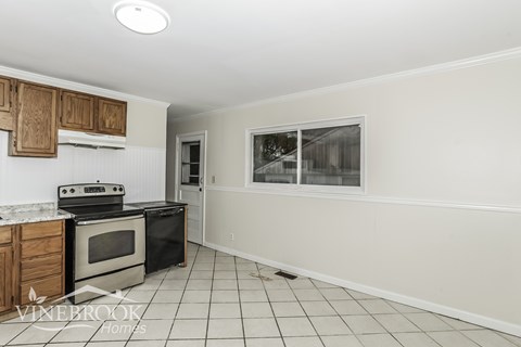 A kitchen with a black stove top oven and white cabinets.