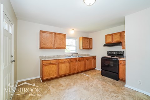 A kitchen with wooden cabinets and a black stove top oven.