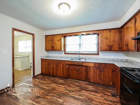 A kitchen with wooden cabinets and a black stove top oven.
