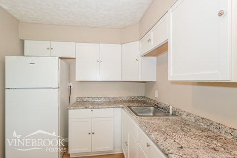 A kitchen with granite countertops and white cabinets.
