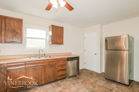 A kitchen with wooden cabinets and a stainless steel refrigerator.
