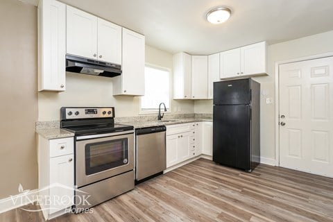 A kitchen with white cabinets and a black fridge.