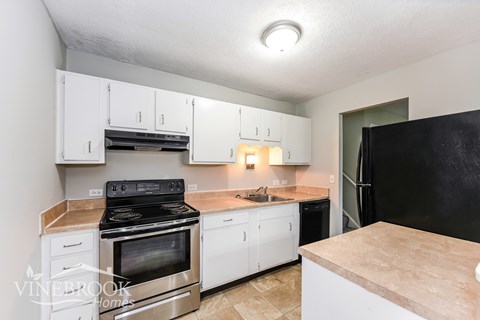 A kitchen with black appliances and white cabinets.
