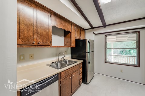 A kitchen with wooden cabinets and a black refrigerator.