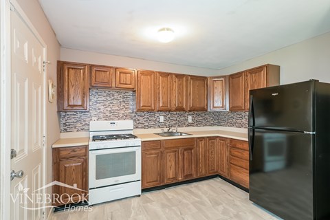 A kitchen with wooden cabinets and a black refrigerator.