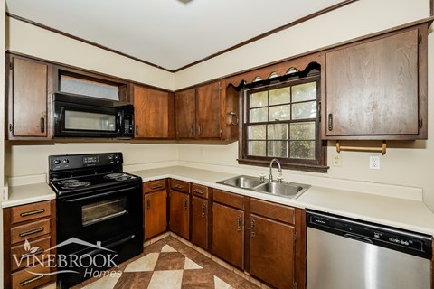 A kitchen with wooden cabinets and a black stove top oven.