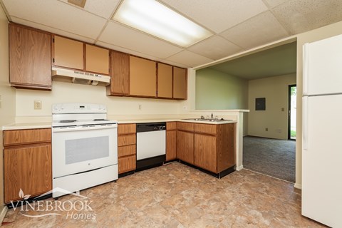 A kitchen with wooden cabinets and a white stove top oven.