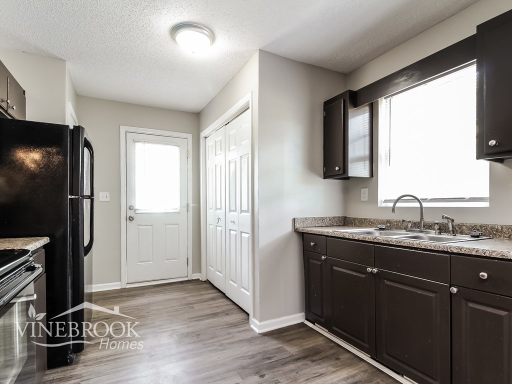 A kitchen with a black fridge and cabinets.